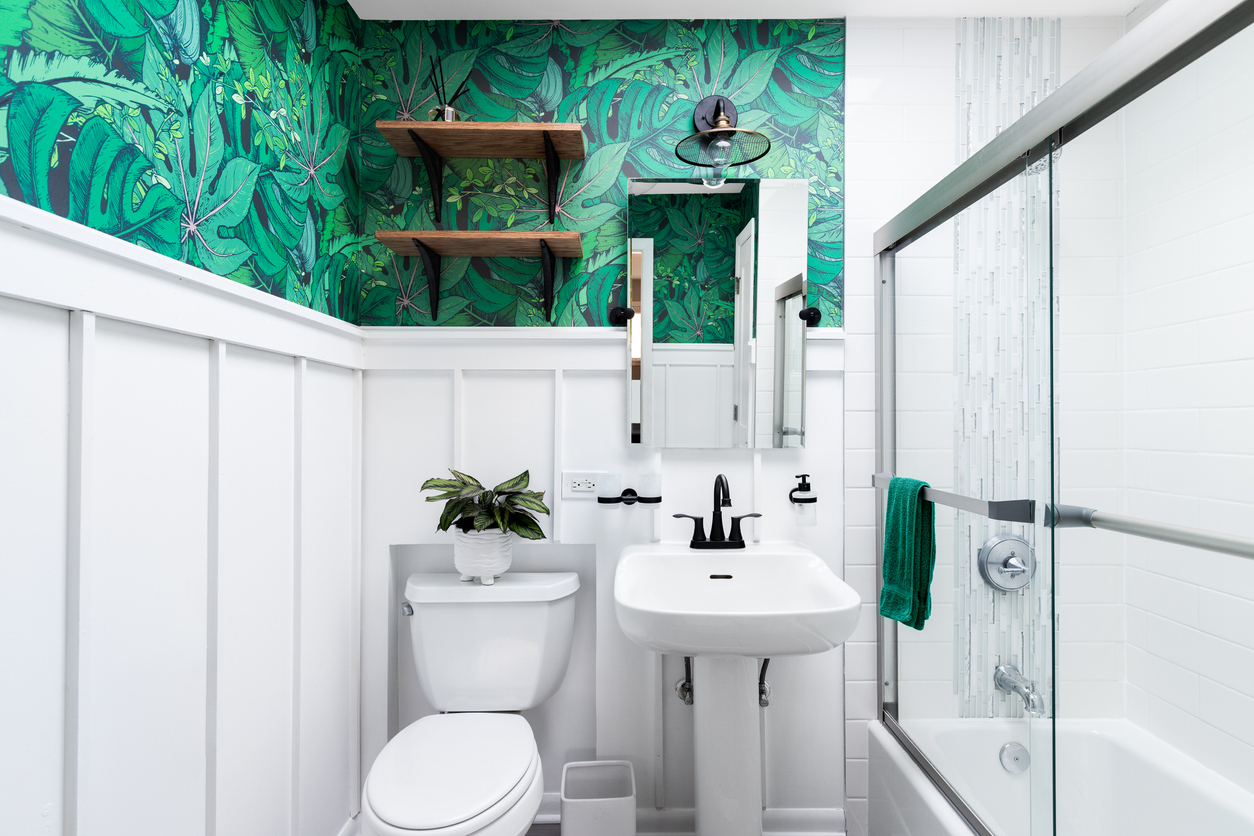 A-small-bathroom-is-decorated-with-white-board-and-batten-topped-with-a-bold-green-botanical-wallpaper.