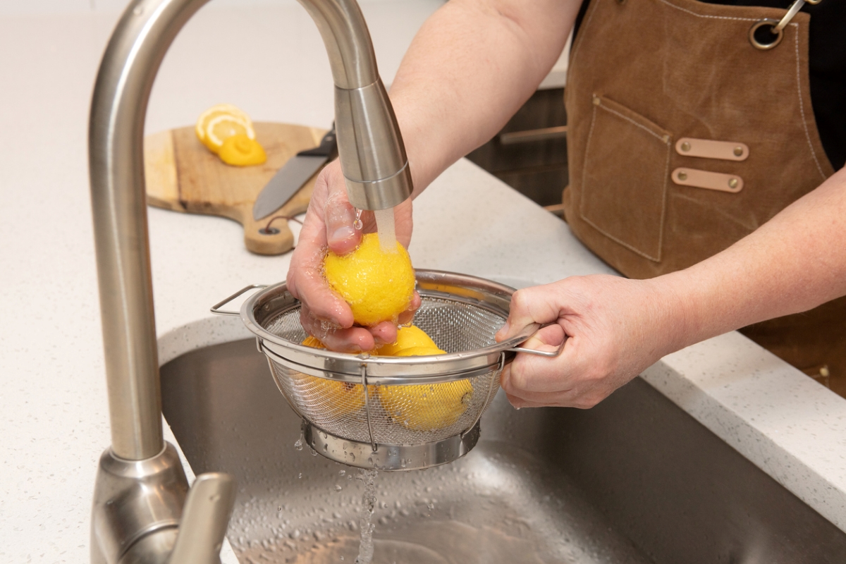 Person washing lemons in sink.