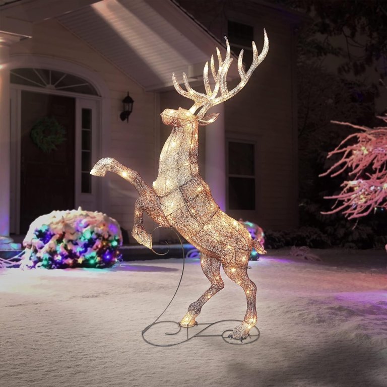 Lighted elk Christmas decoration in the yard of a home at night.