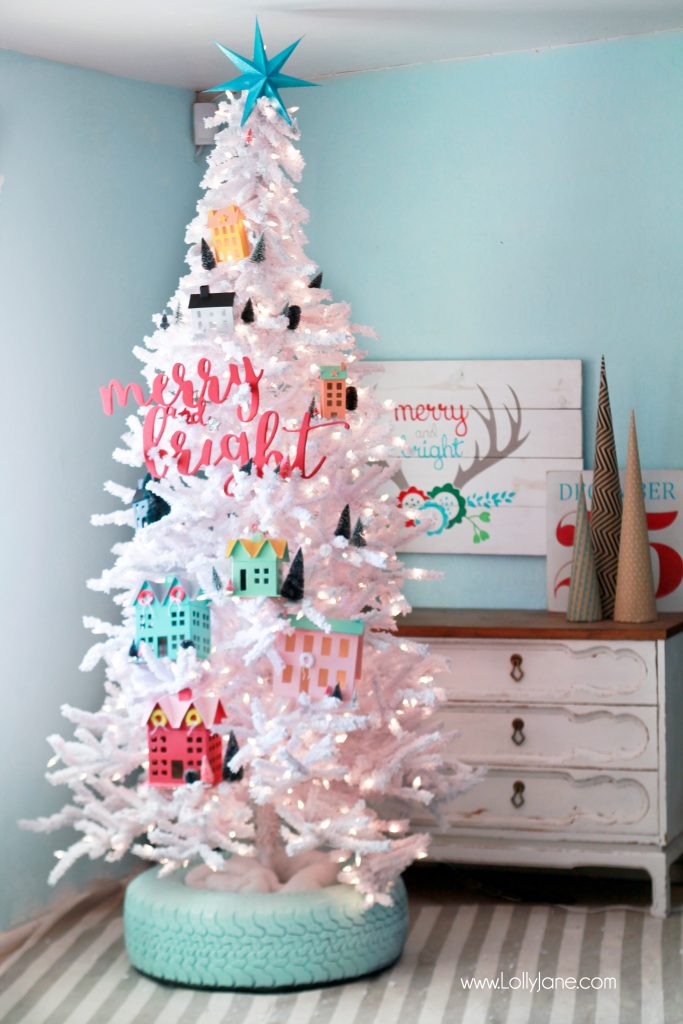A white and pastel colored christmas tree with a tire base painted green.