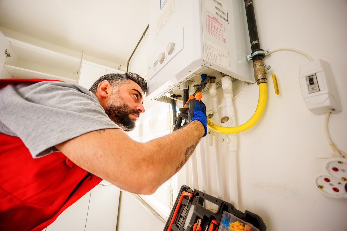 A repairman examines a boiler.