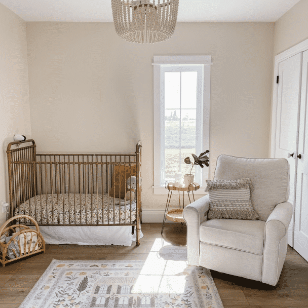 Serene nursery with crib and chair painted in Sherwin-Williams' Accessible Beige.