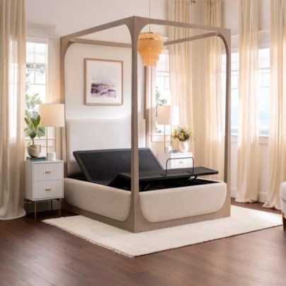 The Purple Premium Plus Smart Base in a canopy bed frame in a bedroom with lots of curtained windows.