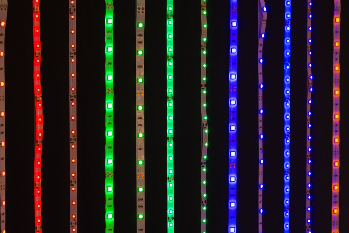 Several outdoor LED strip lights illuminated next to each other on a dark background.