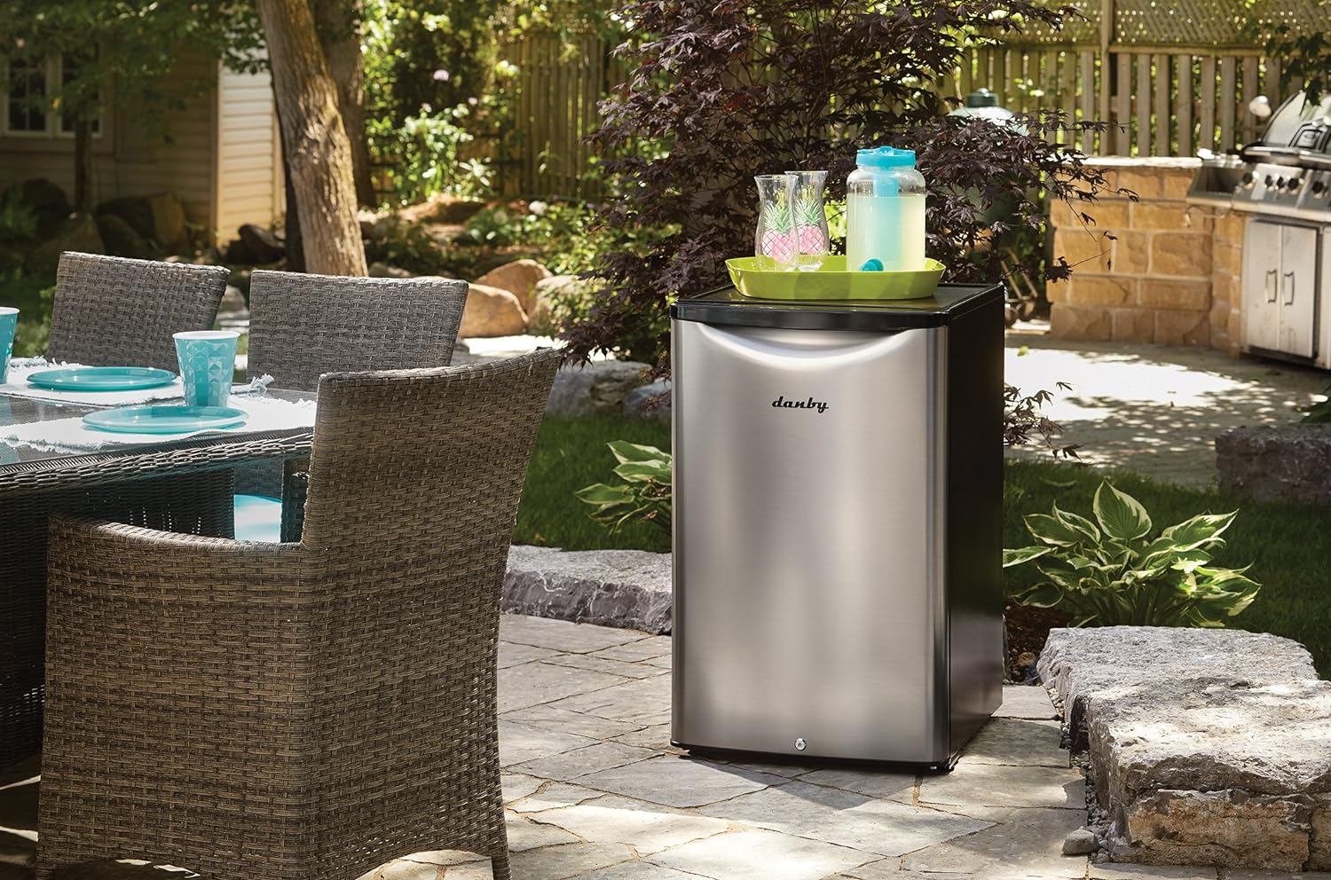 The Danby 4.4 Cu. Ft. Outdoor Fridge on an outdoor patio with a tray of drinks on top.