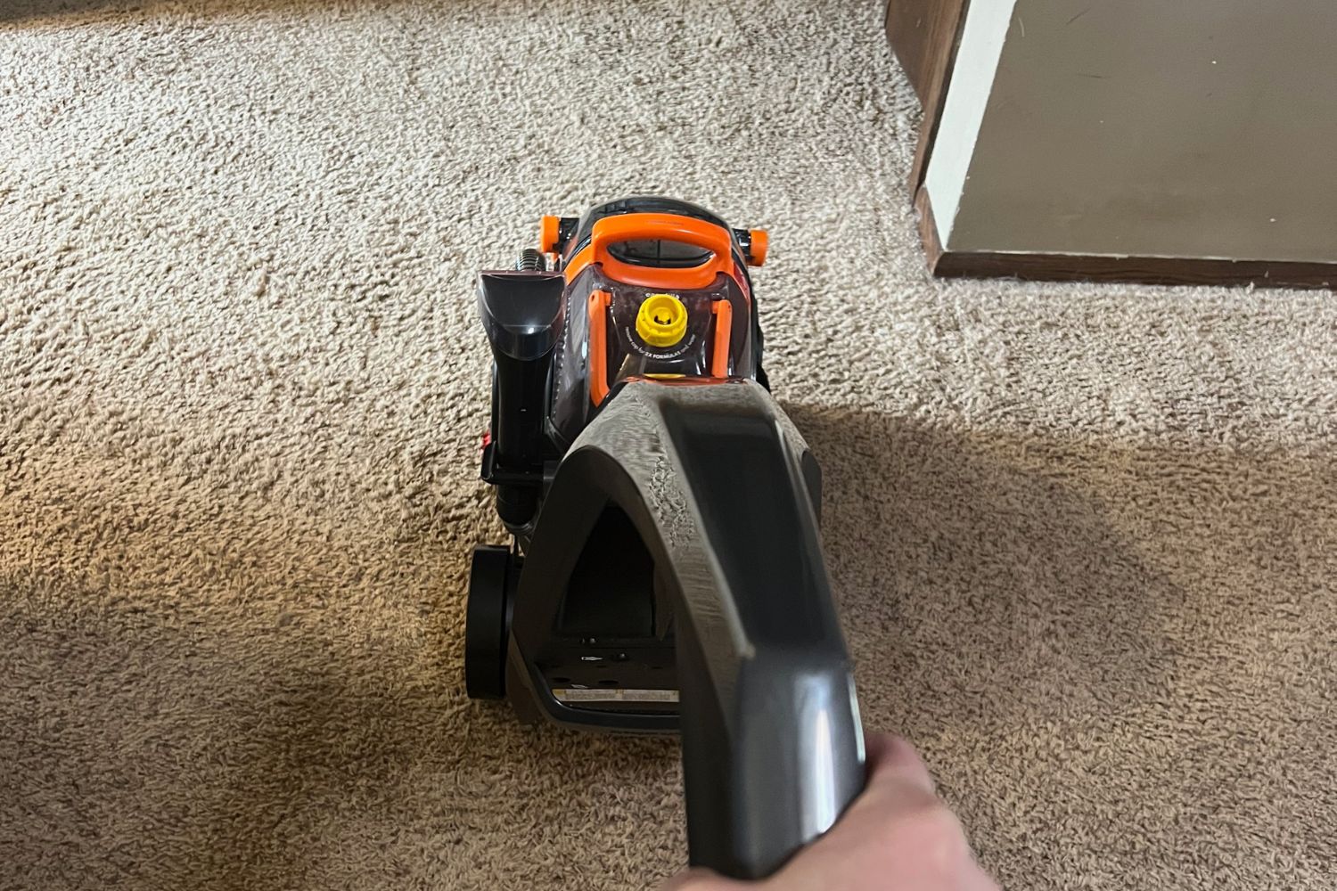 Person cleaning tan carpet with Bissell carpet cleaner