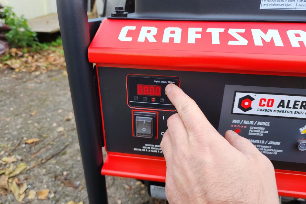 A person pressing the push-button start on the Craftsman 6000-watt generator during testing.