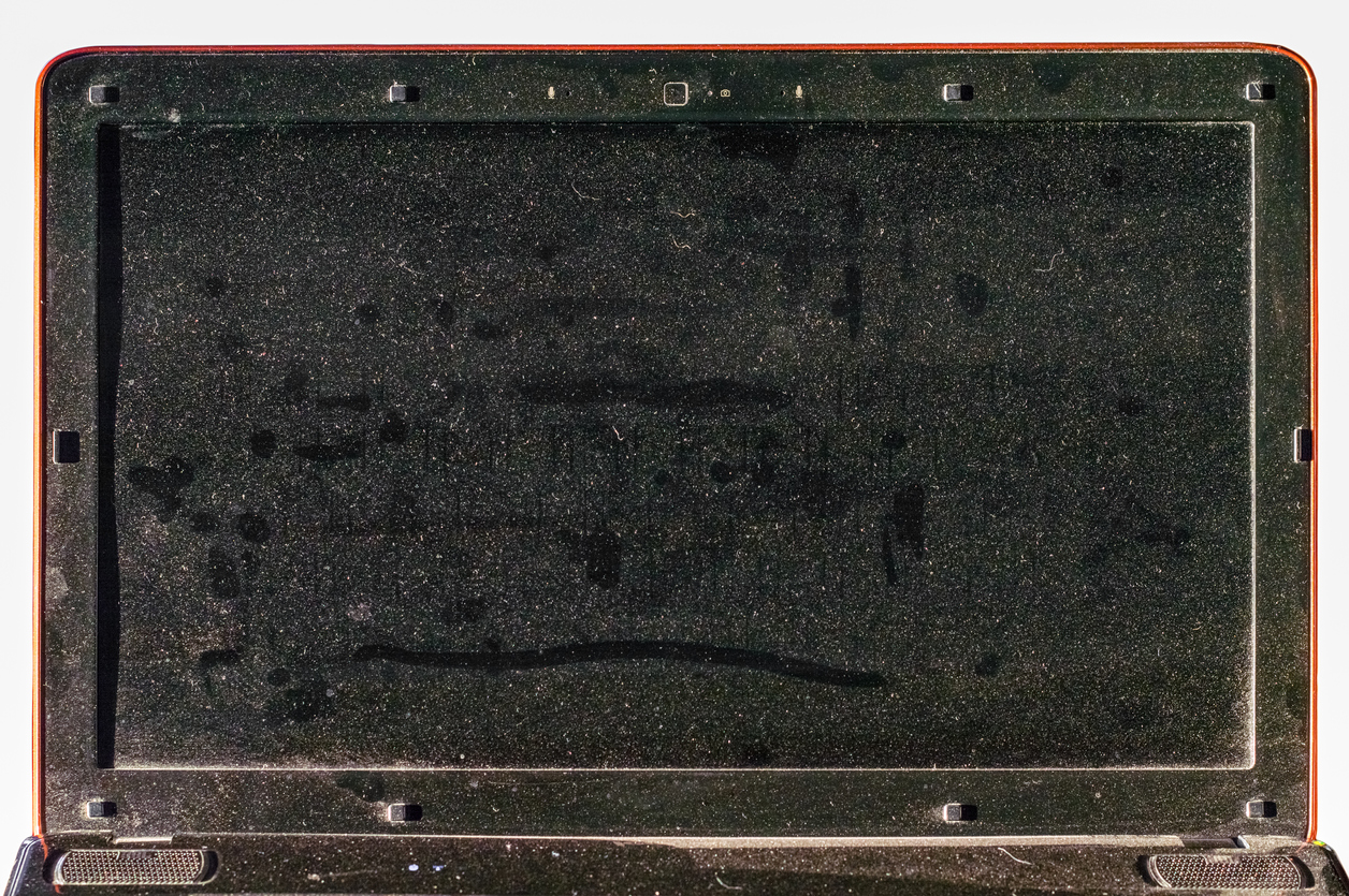 A dust-caked laptop with smears and fingerprints visible on the screen.