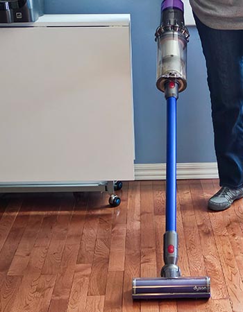 Person vacuuming hardwood floor with Dyson V15 Detect stick vacuum