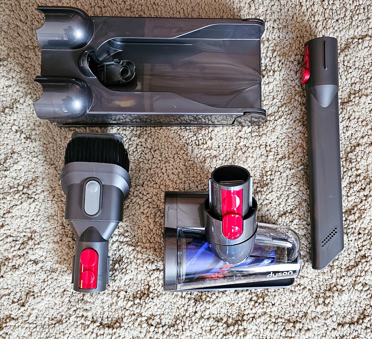 Four gray attachments for the Dyson V15 Detect laying on cream carpet