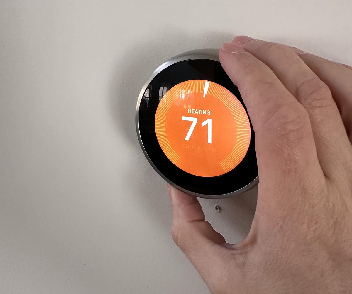 The Google Nest Learning Thermostat installed and showing an orange display face with a temperature reading of 71 degrees Fahrenheit.