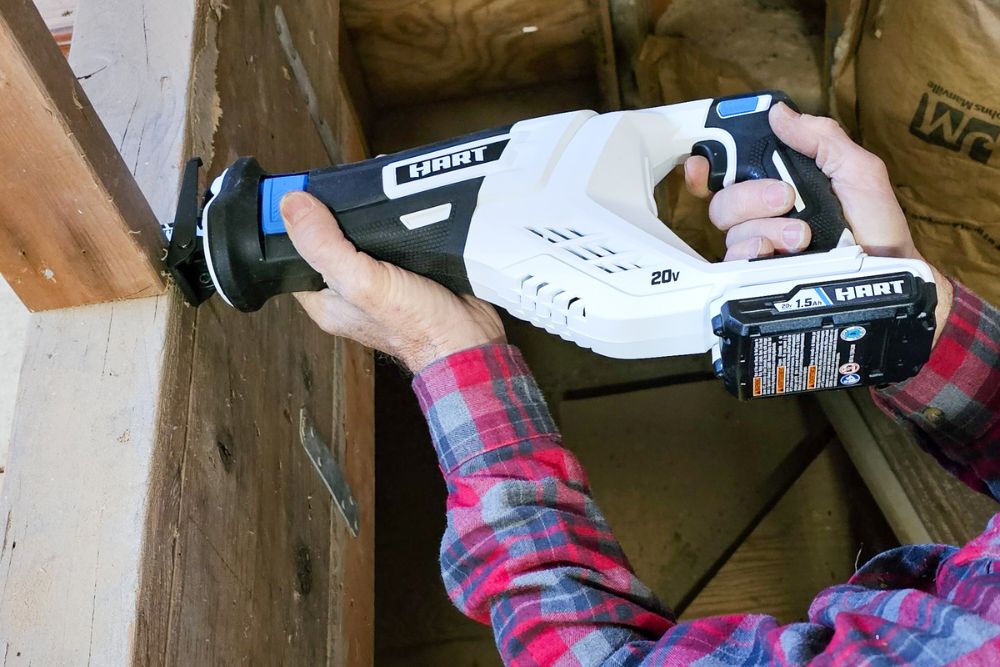 A person using the Hart cordless reciprocating saw to cut a wooden support beam.