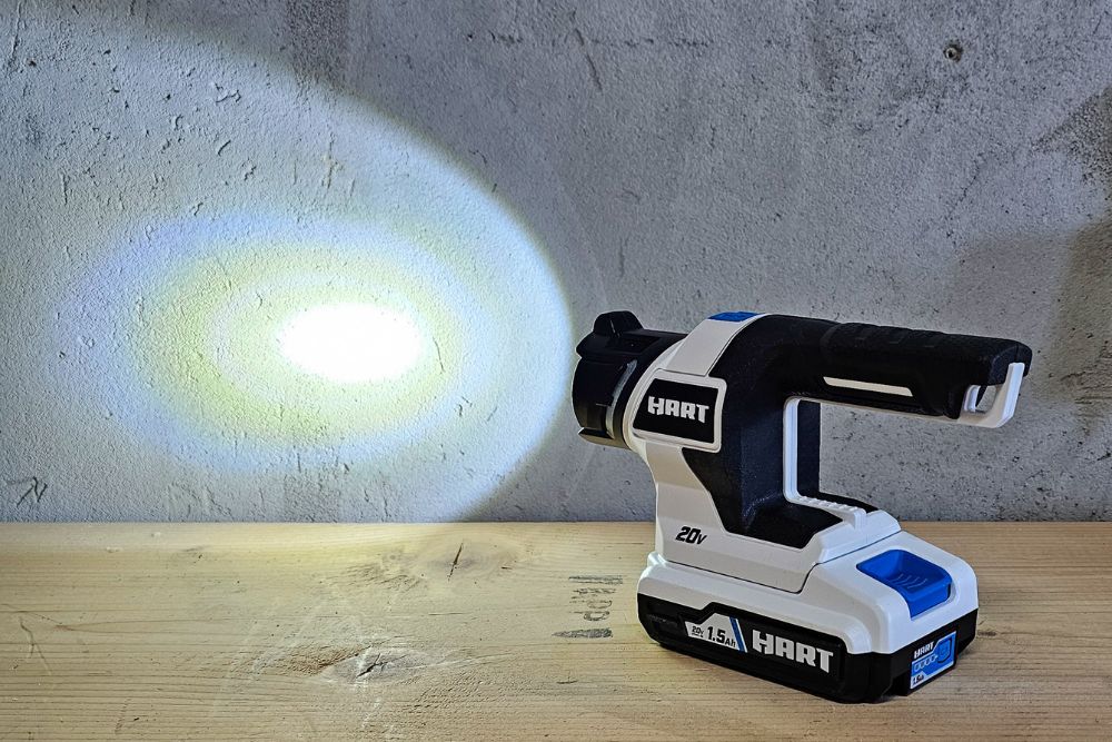 The Hart Tools cordless LED light on a work table and shining on a cement wall.