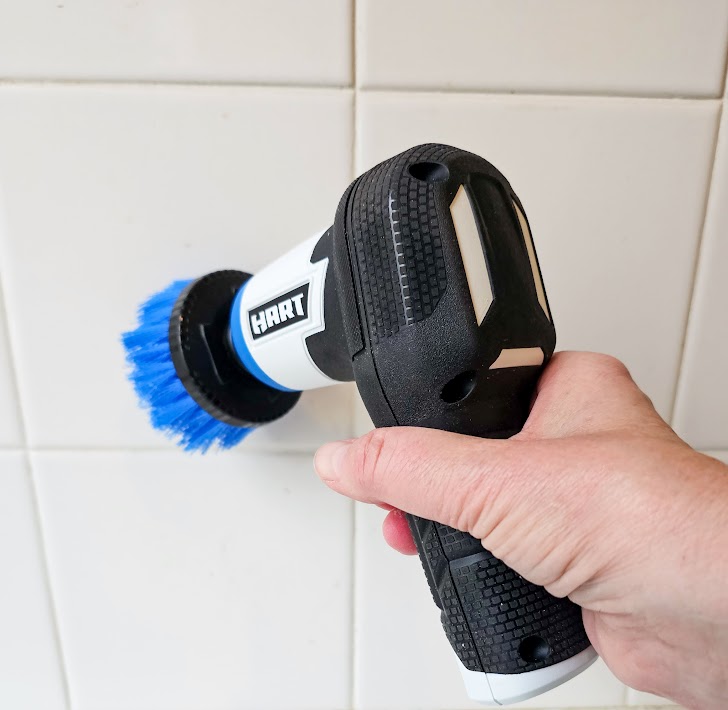A person using the Hart Tools 4V rechargeable scrubber to clean tile.