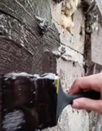 Person using paint brush to apply Liquid Rubber Waterproof Sealant to brick