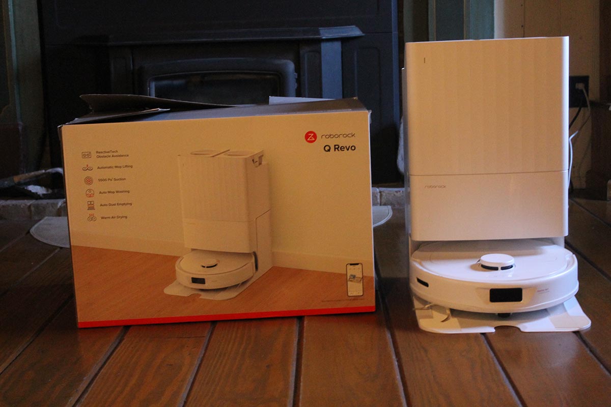 The Roborock Q Revo robot vacuum in its docking station while next to its packaging during testing.