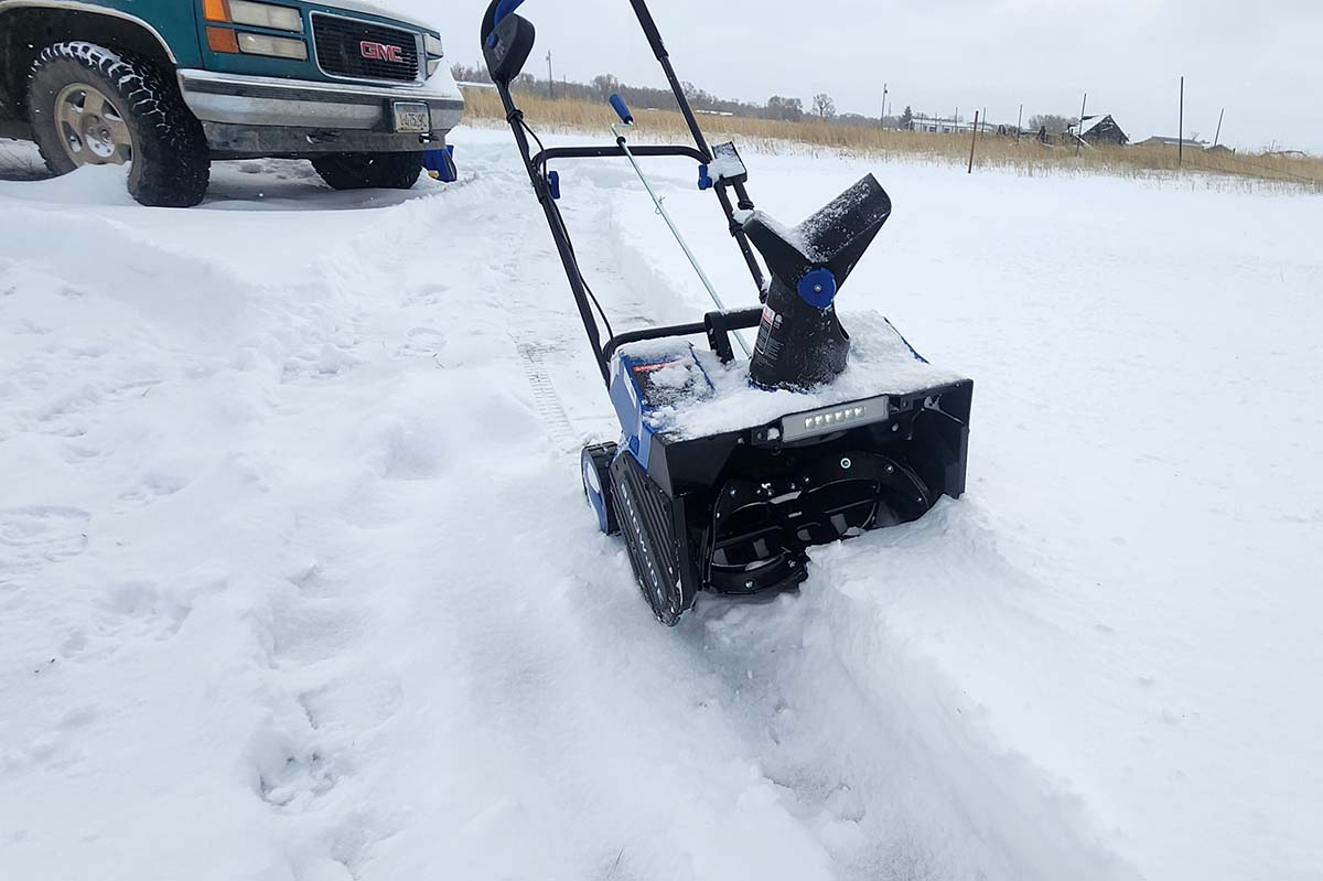 The Snow Joe Single-Stage Snow Blower on a large snow-covered cement pad during testing.