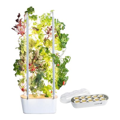 The Gardyn Home Kit 2.0 Hydroponic System growing veggies with a tray of new seed pods next to it.
