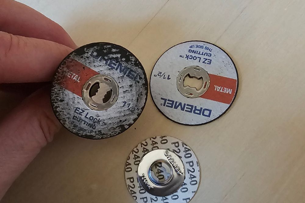 Person holding one rotary blade for Dremel 4300 next to two other rotary blades
