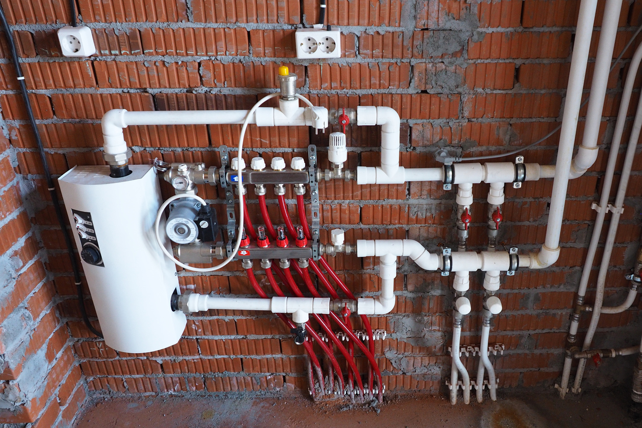 mounted communications in a built house. Electric boiler, heated floor, sockets, water pump, heating, plastic pipes on a brick-free plaster wall.