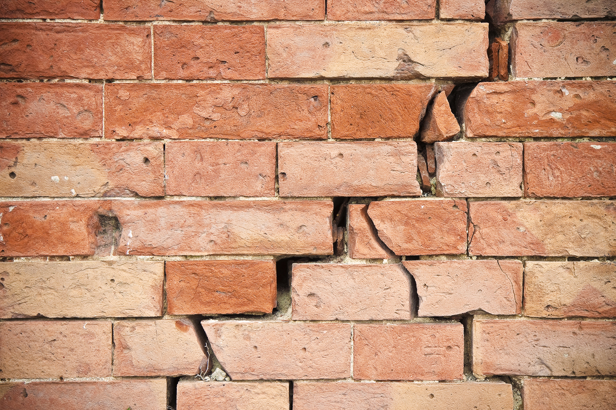 Crack running diagonally down a brick wall or facade.