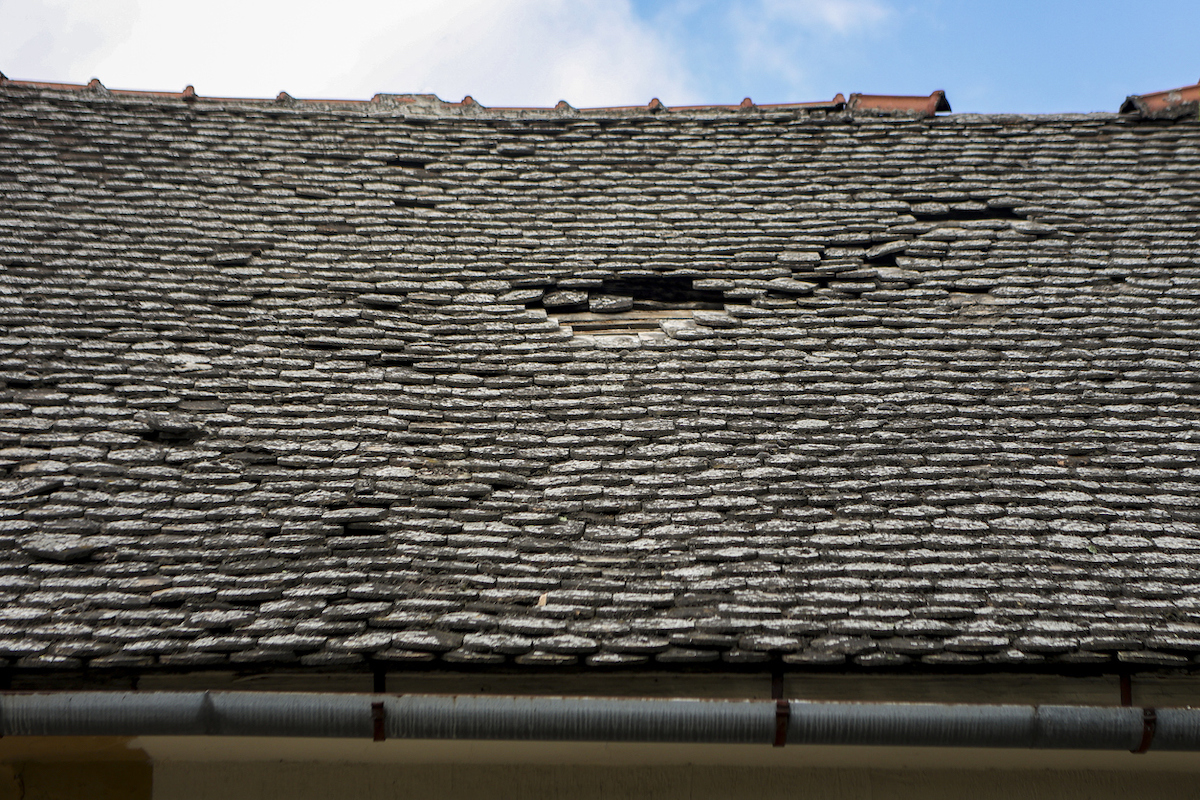 Damaged roof with shingles missing from high winds.