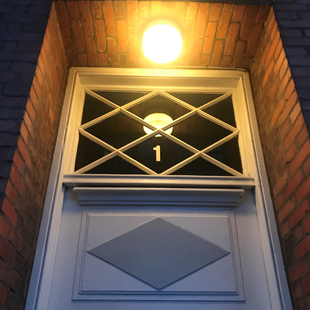 Glass window over a front door with the number 1 on it.