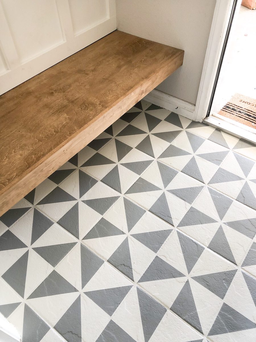 Geometric gray tile in an entry with a natural wood bench.