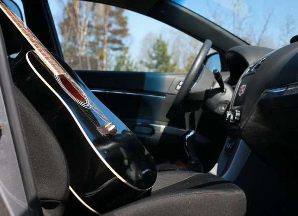 Black acoustic guitar on front seat of car