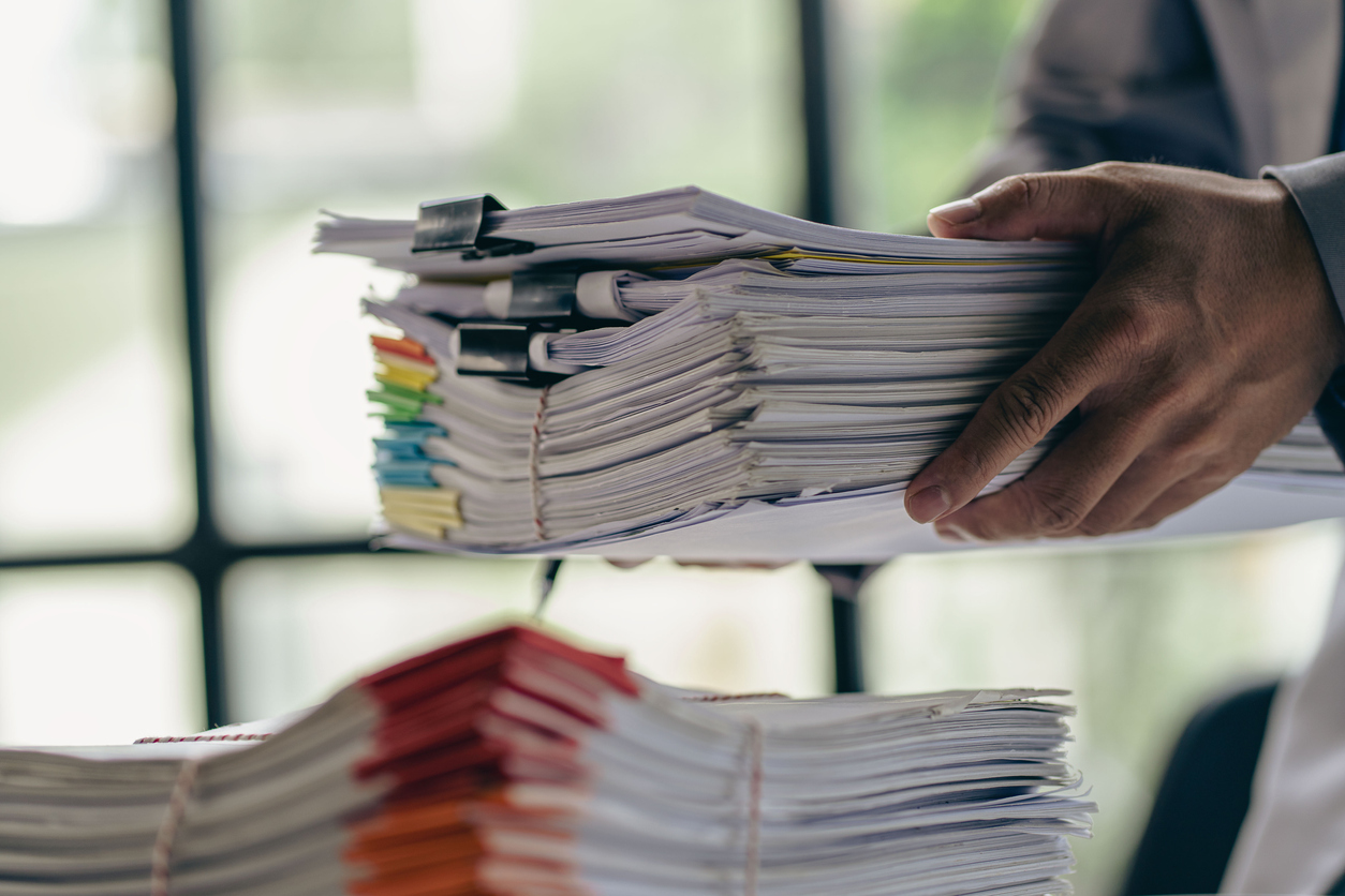 Business administration and information documents on the desk Excessive pile of papers of businessman holding many papers