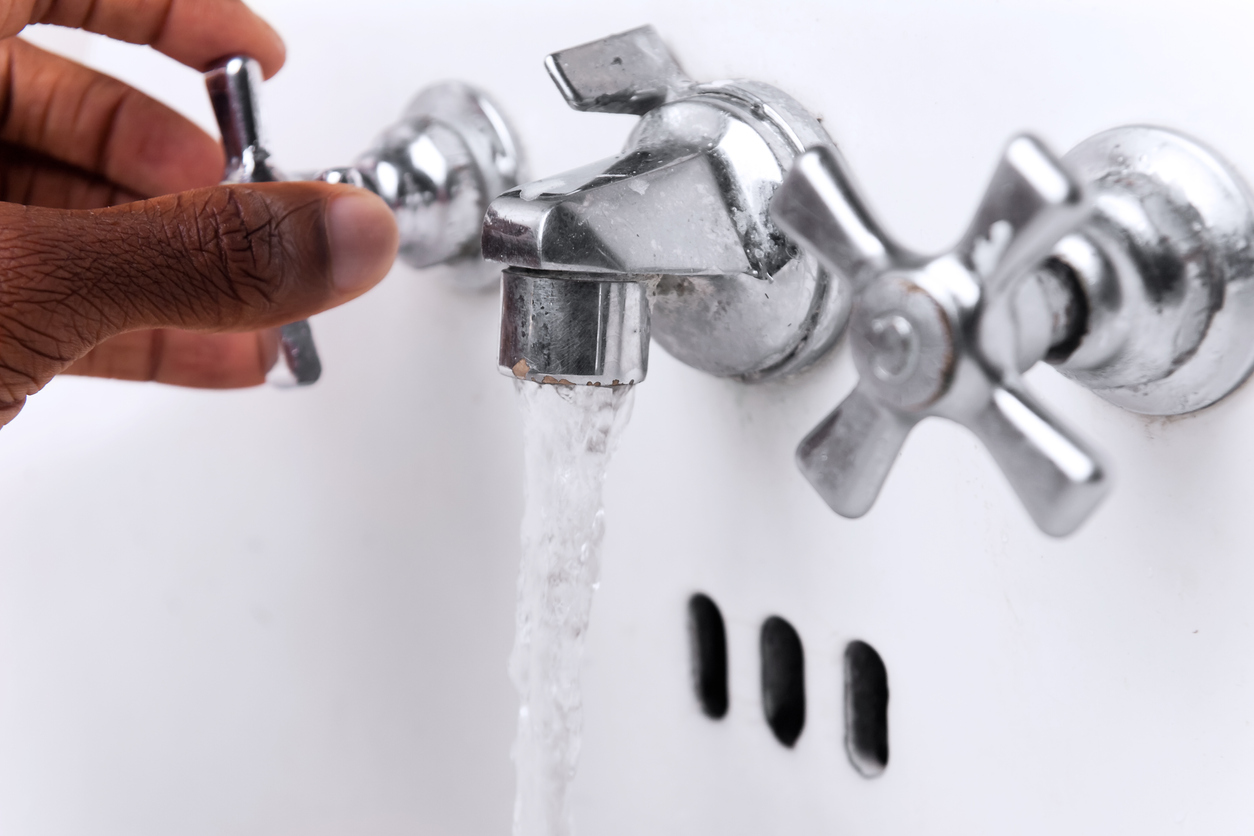 A hand turning a Faucet off to save water