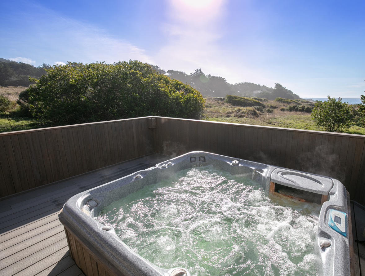 Hot tub on deck with scenic view of landscape.