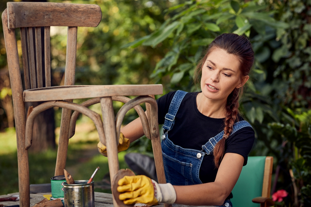 Woman working on outdoor wooden chair.