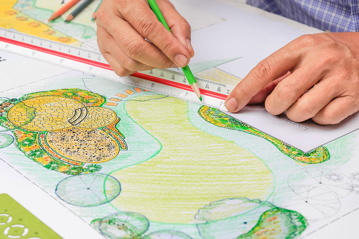 A person drawing out a diy landscape design for their backyard.