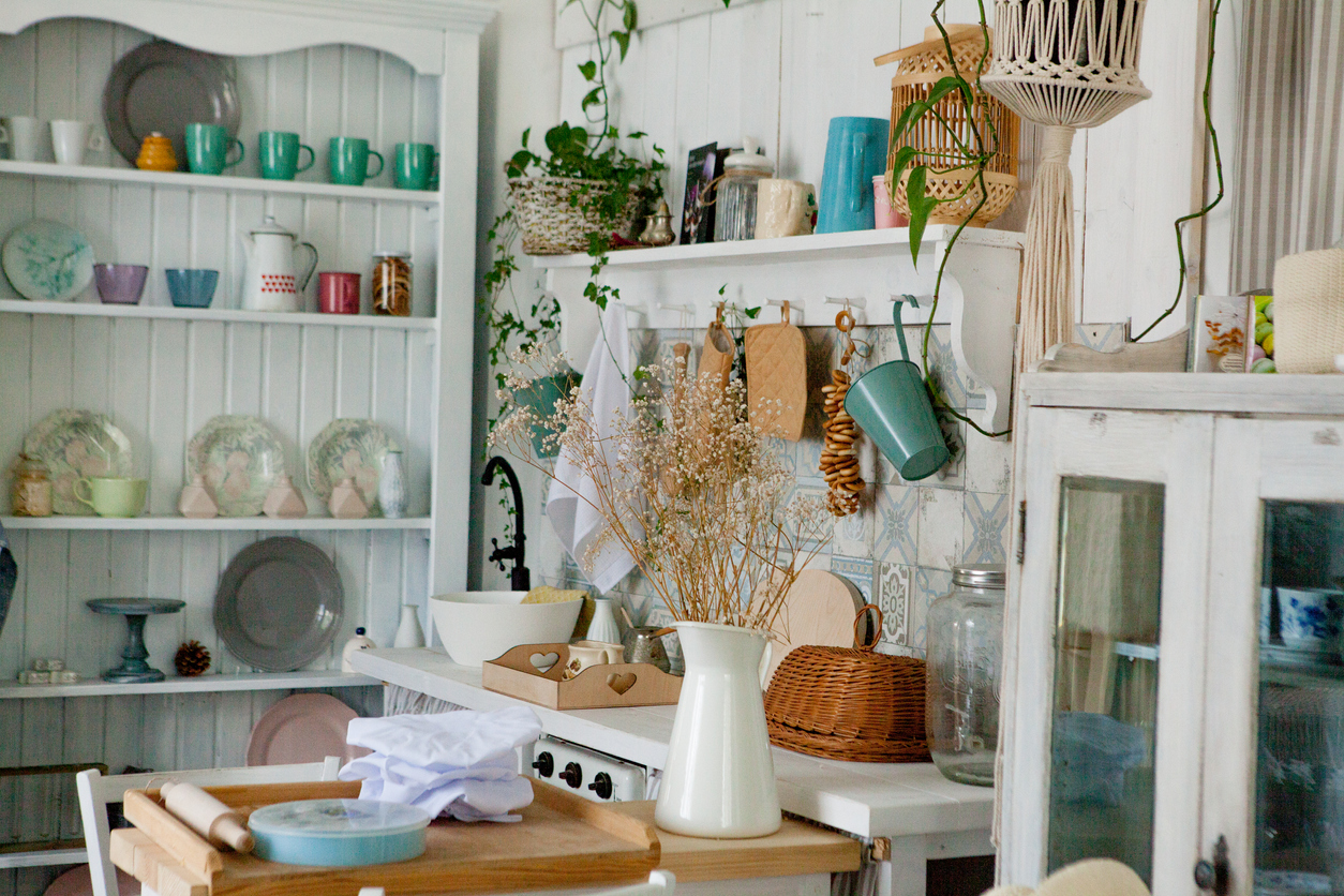 A-collection-of-vintage-dishes-and-mugs-is-displayed-on-shelves-in-a-cluttered-cozy-kitchenette.