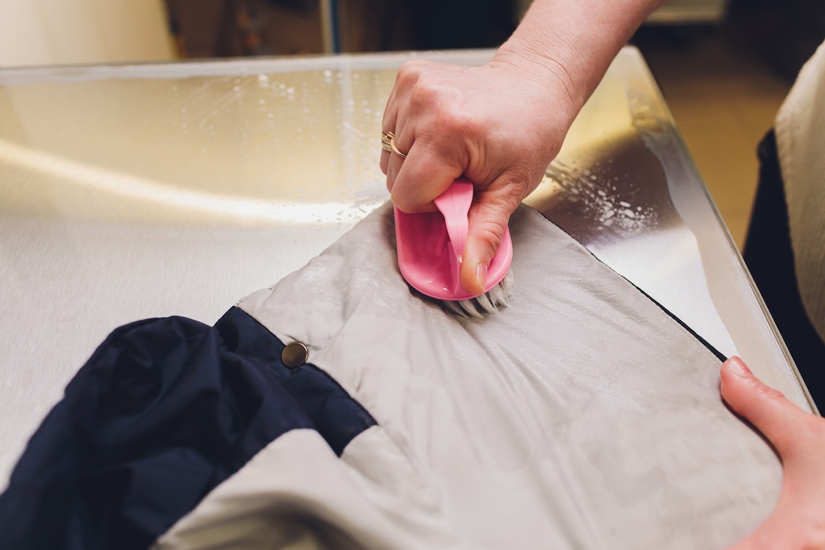 A person scrubbing vinegar on clothing to remove stains.