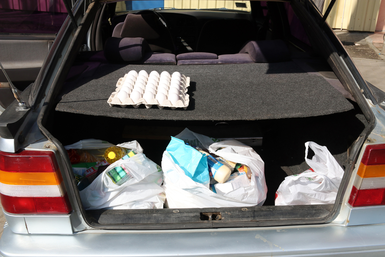 Plastic shopping bags with food in the trunk of a car. COVID-19.