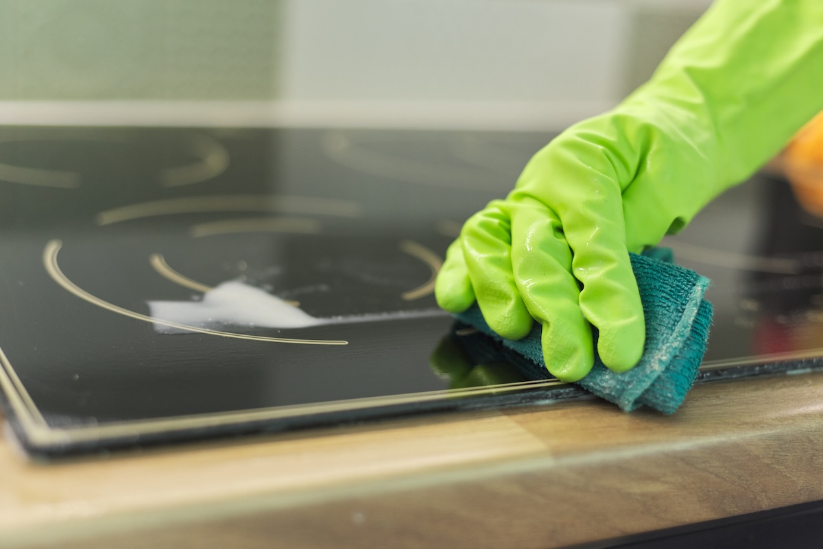 A person rinsing an induction cooktop after cleaning the surface.