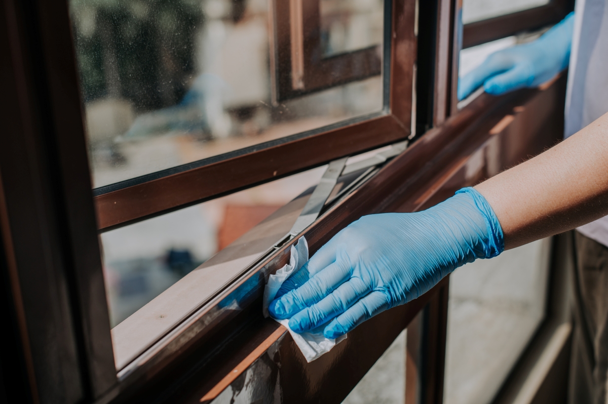 Gloved hands cleaning windowsills.