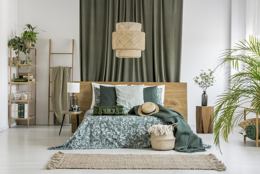A-green-curtain-hangs-behind-the-head-of-a-bed-in-a-green-and-brown-boho-bedroom.
