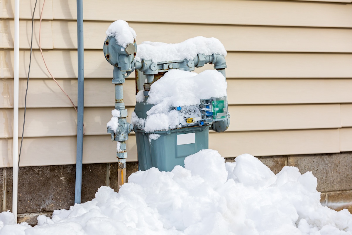 A residential gas meter outside of a home covered in snow during winter when gas bills might spike because of usage.