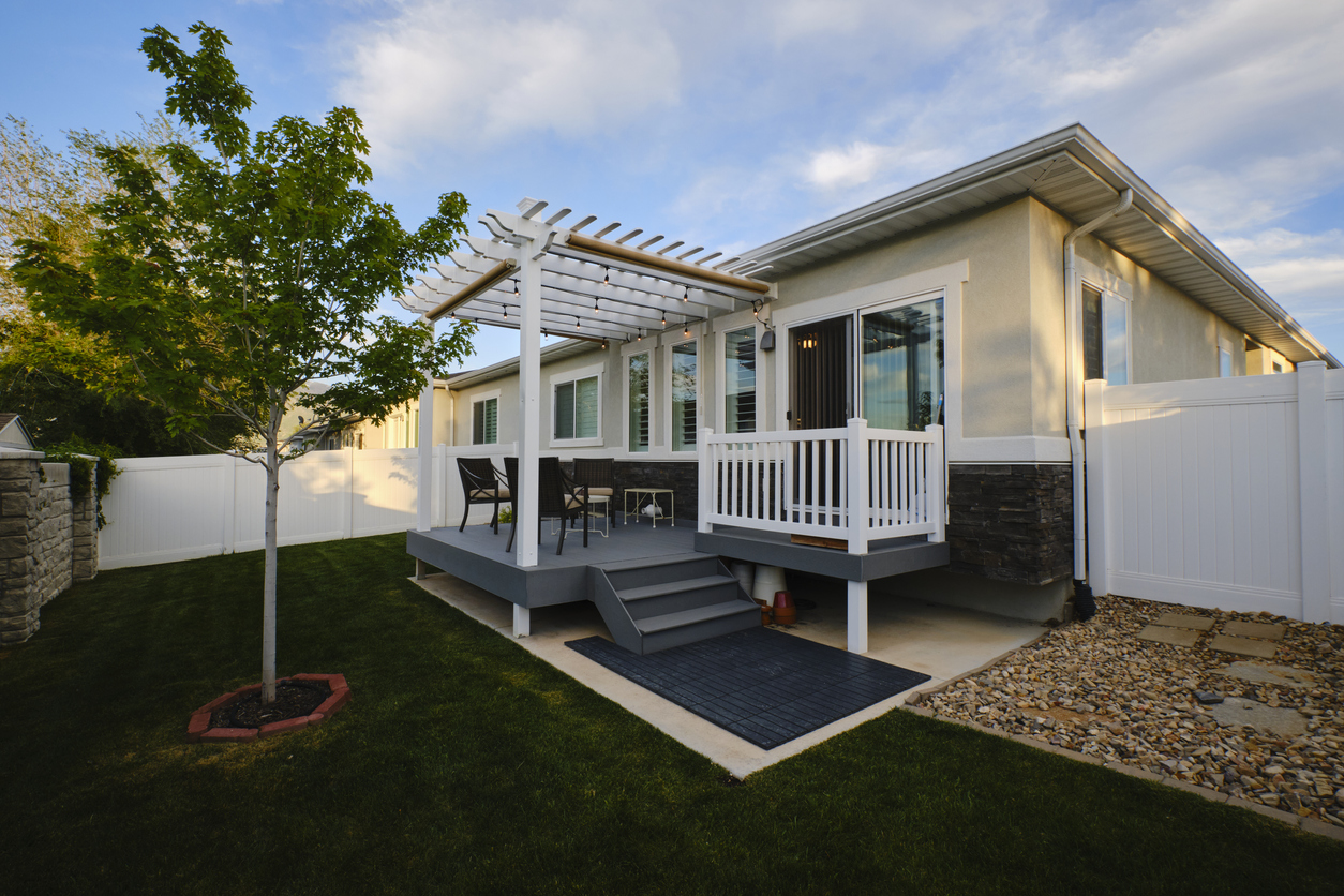 Tan home with small pergola and deck.