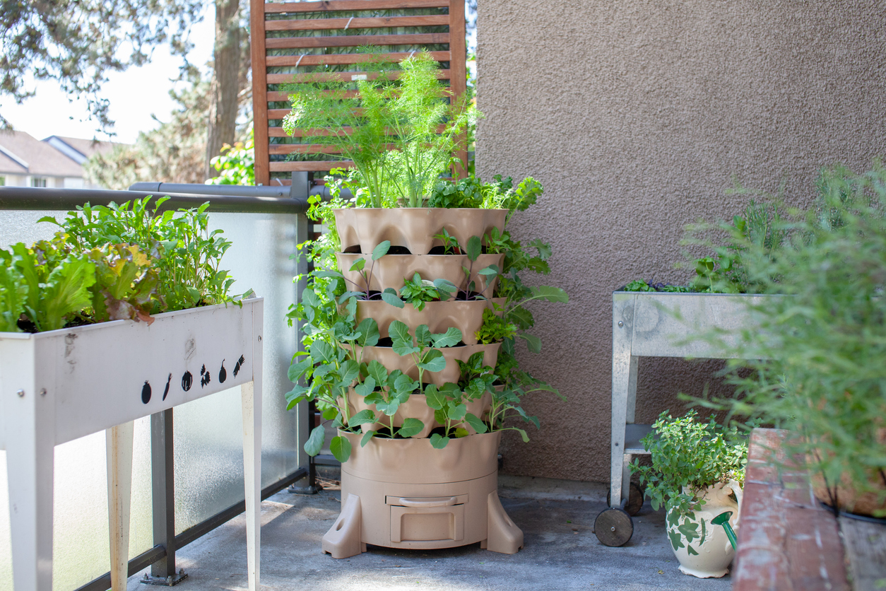 A-vertical-garden-container-sits-in-the-corner-of-a-patio-with-other-planters.
