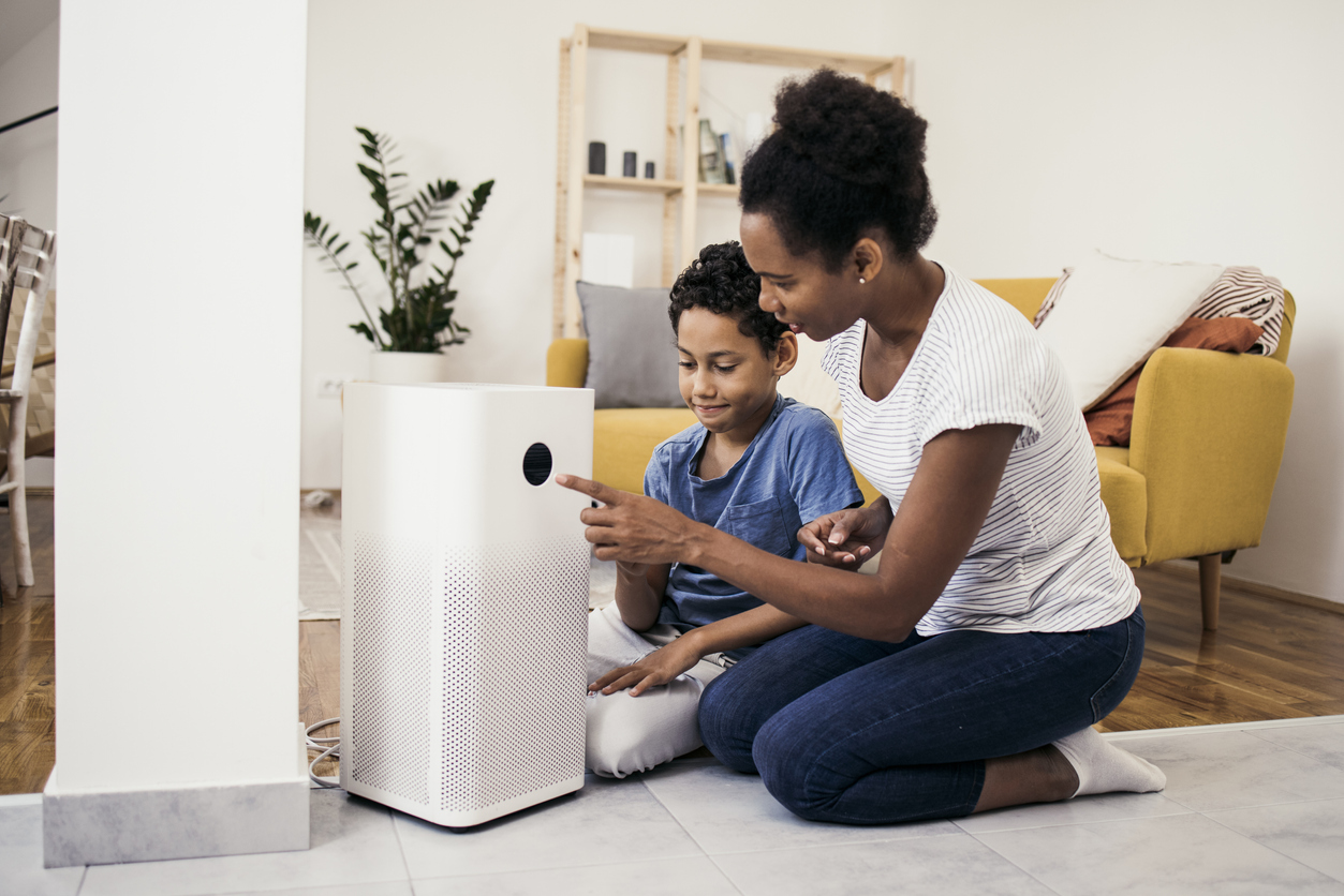 A woman and her son setting up an air purifier in their living room.
