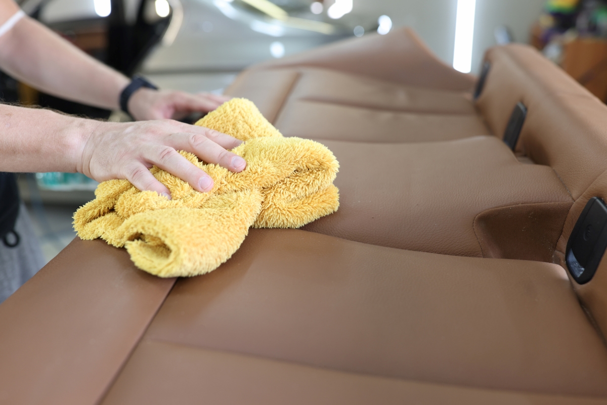 Cleaning leather car seats with yellow towel.