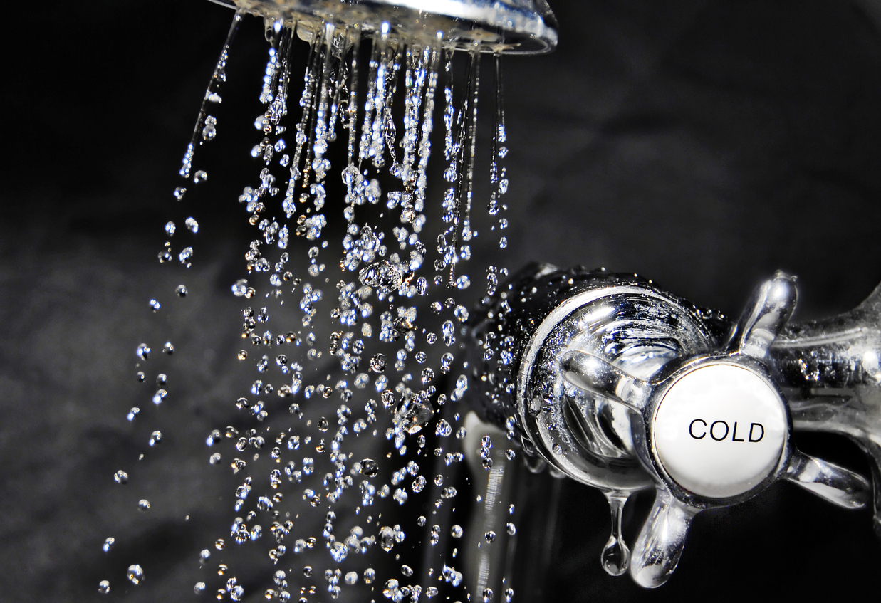Chrome bath tap and water flowing from shower head