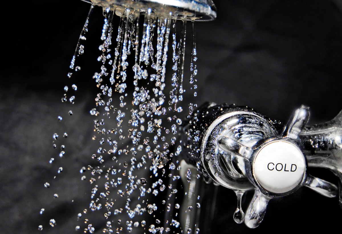 Chrome bath tap and water flowing from shower head