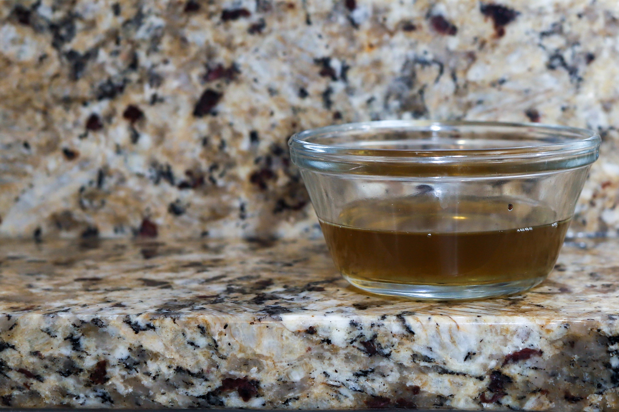 A glass jar of vinegar on a kitchen counter to attract gnats and flies