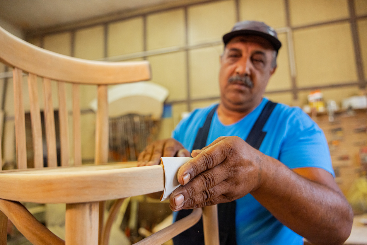 Indian carpenter making a wooden chair. Removing rough surfaces on wood.