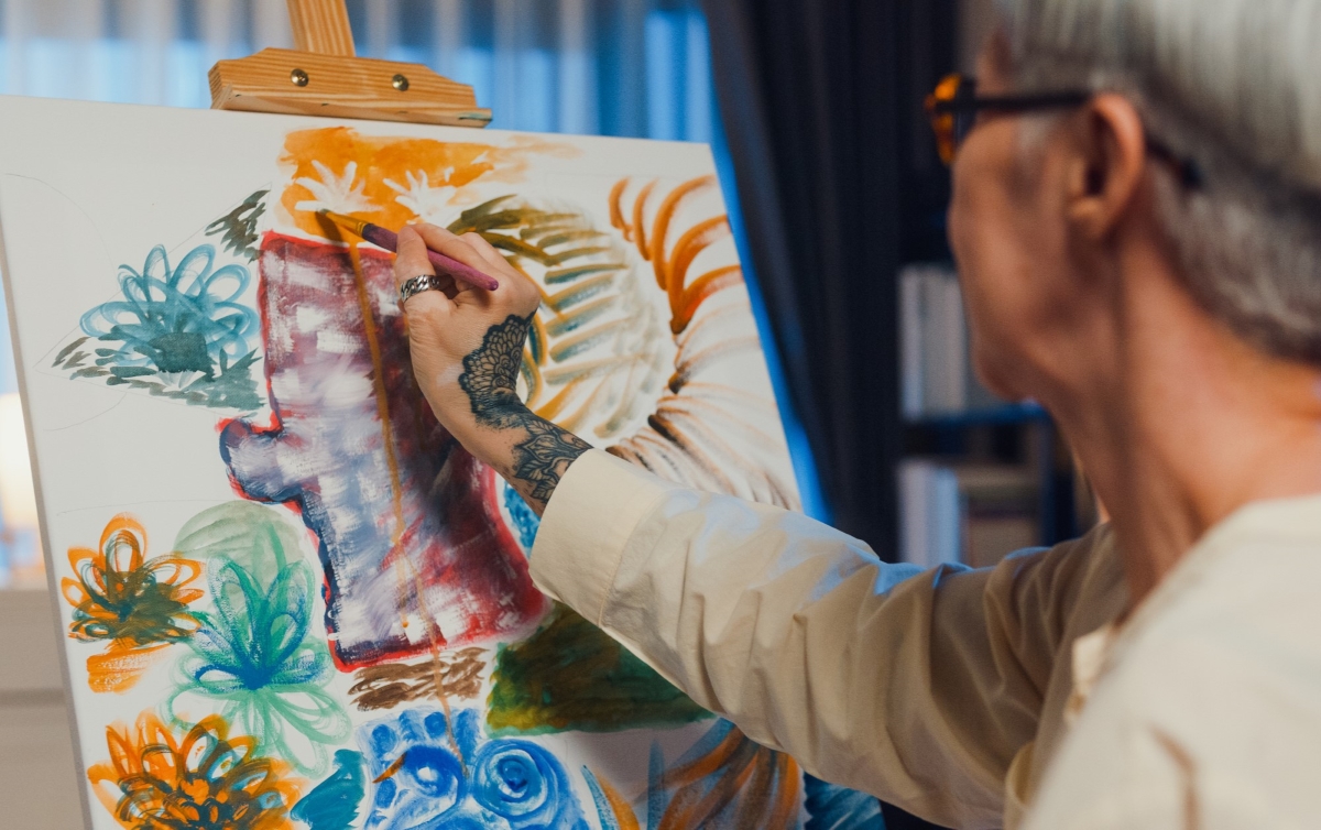 Elderly woman doing art on canvas.